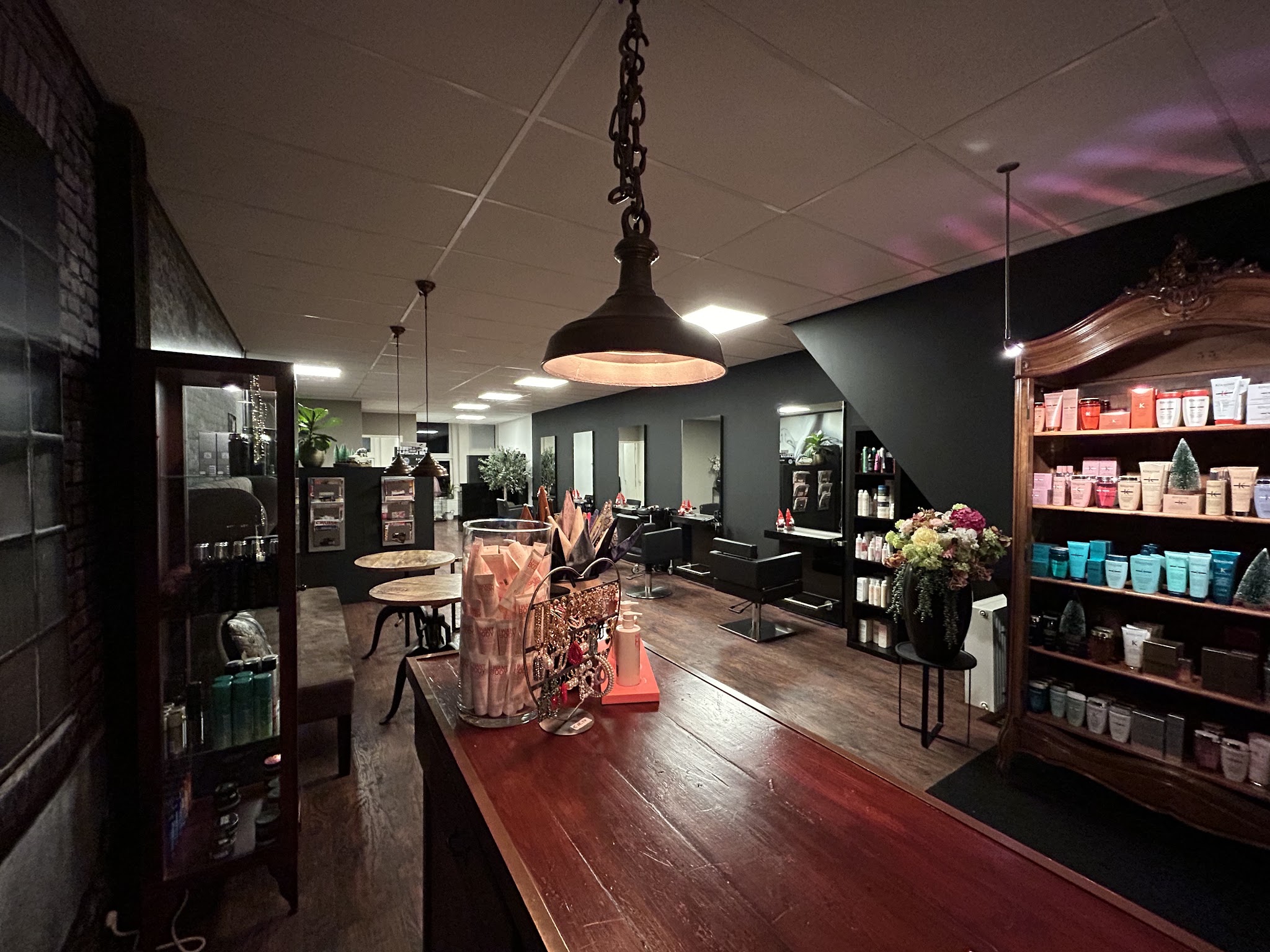 De lange houten balie en productwand in de salon